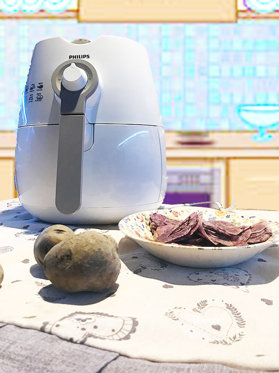 macchina per friggere ad aria e piatto con patate posizionati su un tavolo coperto dalla tovaglia