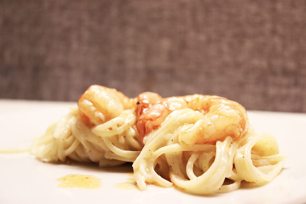 ciotola bianca con pasta caco e pepe con gamberi e foglia di cerfoglio