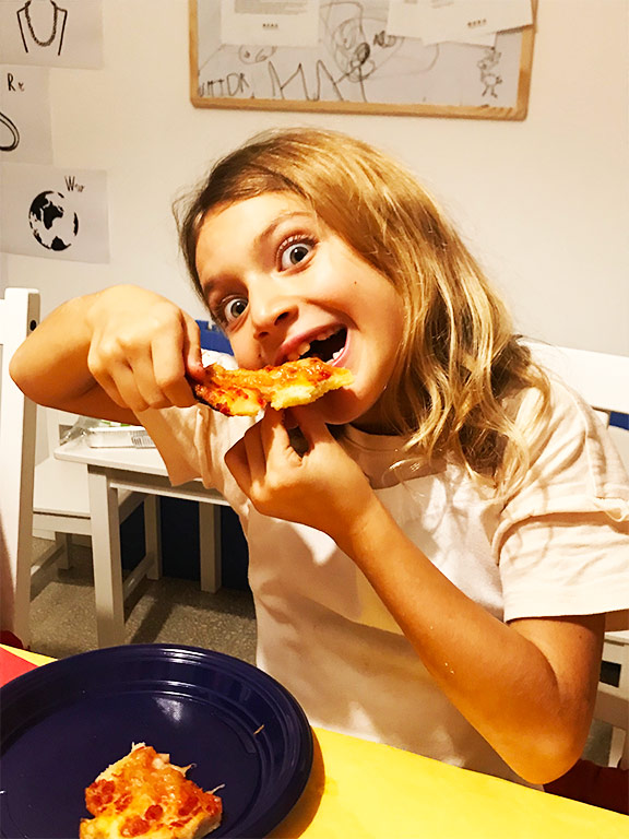 foto di una bambina che mangia pizza rossa