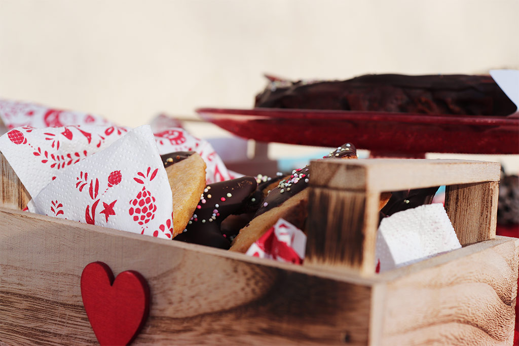 foto di una piccola cassetina in legno con un cuore rosso riempita con biscotti