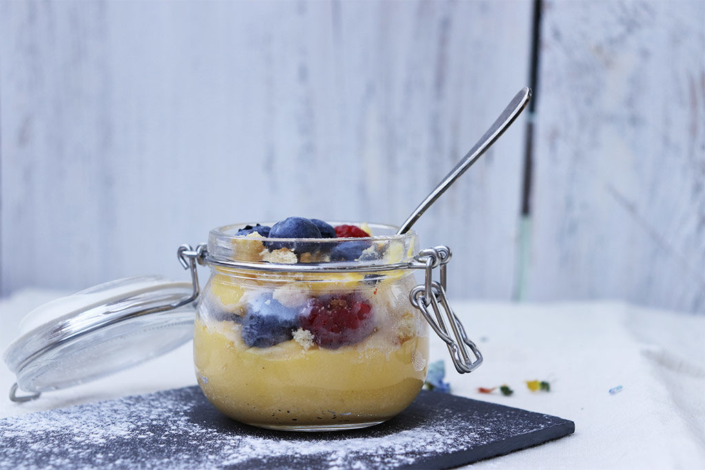 foto in primo piano di un barattolino di crema con frutti di bosco